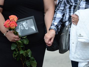 Family members of Michael MacIsaac hold a photo of him, while holding hands at a demonstration last fall at Queen's Park for people affected by fatal police shootings.
