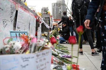 People leave flowers at a memorial on Yonge Street the day after a driver drove a rented van down sidewalks Monday afternoon, striking pedestrians in his path in Toronto, Tuesday, April 24, 2018. THE CANADIAN PRESS/Galit Rodan