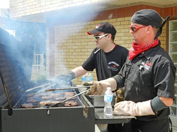 Andy and Dave of BBQ Feast Catering grill up a batch of burgers at the Making Miracles charity barbeque at Victoria Park Friday (May 17).                               