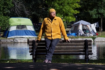 David Alton stands near the encampment on Roos Island in Victoria Park Friday. Alton is the facilitator of Kitchener’s homelessness Lived Expertise Working Group.