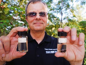 Peter Jekel, manager of environmental health at the region, holds jars containing black legged ticks and American dog ticks at Rotary Park in St. Catharines on Wednesday.