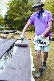 Jerry Overboom paints wood siding during the Volunteer Builders’ recent project at Ryde Lake Camp.