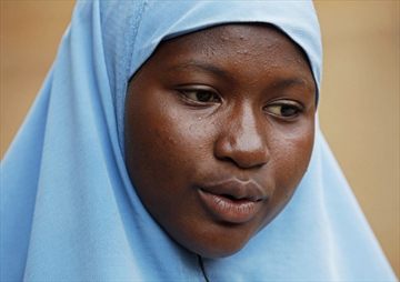 Maimuna Abdullahi sits outside her school in Kaduna, Nigeria. Maimuna wore the scars of an abused woman anywhere: A swollen face, a starved body, and, barely a year after her wedding, a divorce.