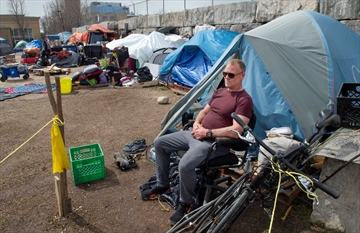 Mark Ashley sits in front of his tent at an encampment at Weber and Victoria streets.