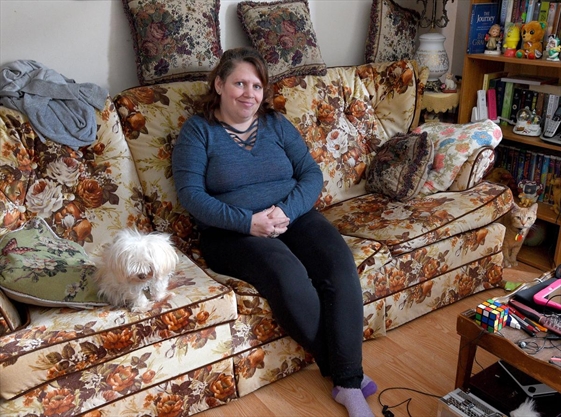 Tammy Hudgins in her home with her dog Lady and one of her cats..